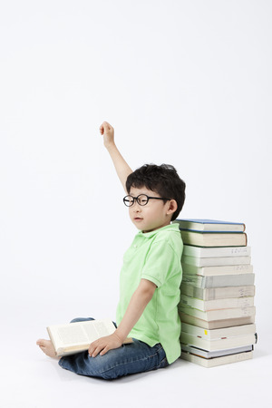 Asian smart boy answering the question next pile of books isolated on whiteの写真素材