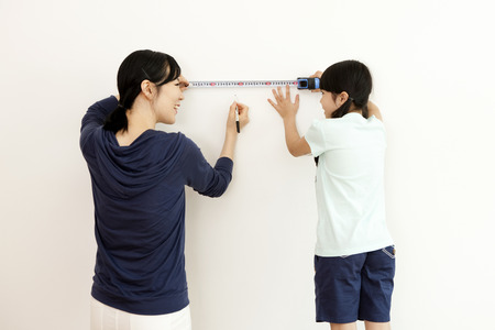 Rear view of Asian mother and daughter measure something with a tapelineの写真素材