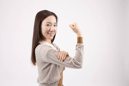 Close up Asian beautiful woman flexing her biceps isolated on whiteの写真素材
