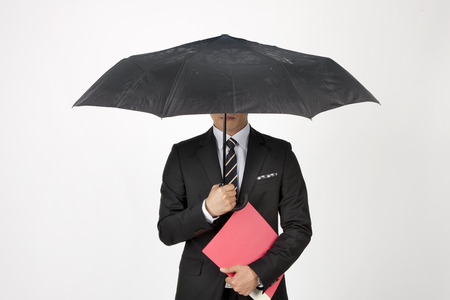 Close up Asian business man holding black umbrella isolated on whiteの写真素材