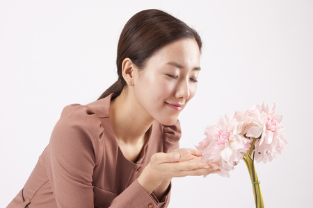 Close up Asian business woman smelling the flower isolated on whiteの写真素材