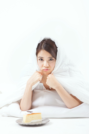 Asian beautiful woman eating cake isolated on whiteの写真素材