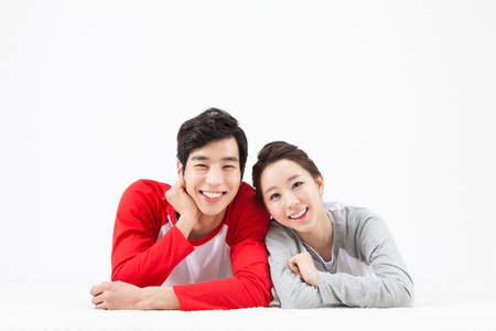 Asian happy couple lying on lug together with smile isolated on whiteの写真素材