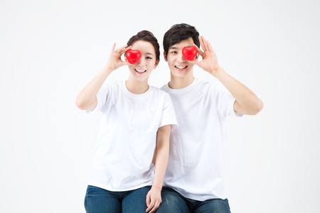 Asian happy couple dressed white t shirt with heart ball isolated on whiteの写真素材