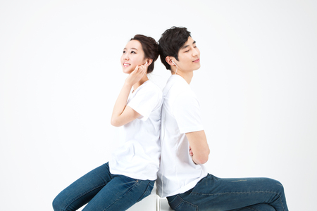 Asian happy couple dressed white t shirt listening music isolated on whiteの写真素材