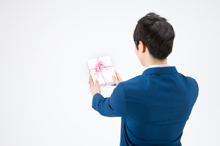 Rear view of Asian handsome man holding pink gift box isolated on whiteの写真素材
