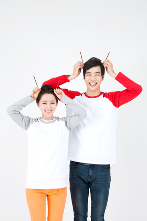 Asian happy couple having fun with piece of chocolate isolated on whiteの写真素材