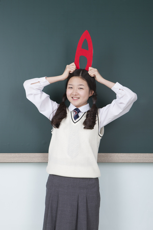 Asian middle school girl holding A grade sign on her head isolated on whiteの写真素材