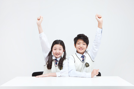 Asian middle school boy and girl answering the question isolated on whiteの写真素材