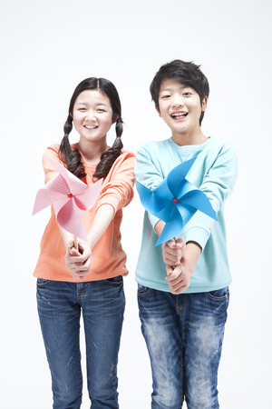 Asian teenager boy and girl playing with pinwheel isolated on whiteの写真素材