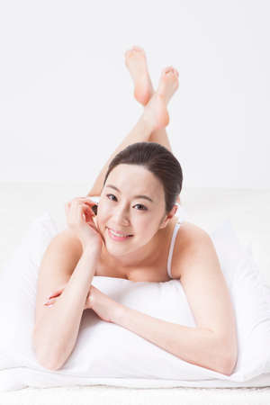 Portrait of Asian beautiful woman lying and relaxing on the floor isolated on whiteの写真素材