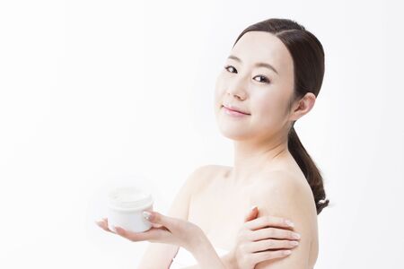 Portrait of Asian closeup beautiful woman holding moisturizer cream isolated on whiteの写真素材