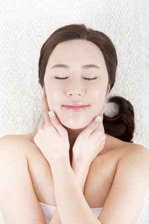 Portrait of top view Asian beautiful woman lying on the studio hand touch her face with closing her eyes isolated on whiteの写真素材