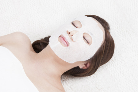 Portrait of top view Asian beautiful woman lying and relaxing with facial mask isolated on whiteの写真素材