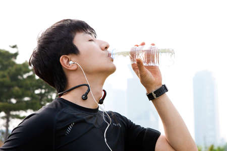 Portrait of closeup Asian leisurely male drinking water in outdoor parkの写真素材