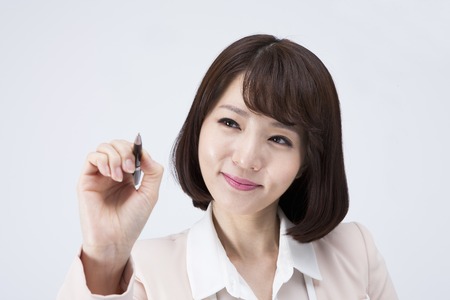 Portrait of Asian female teacher writing something with smile isolated on whiteの写真素材