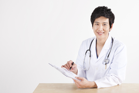 Portrait of Asian male doctor holding document with smile isolated on whiteの写真素材