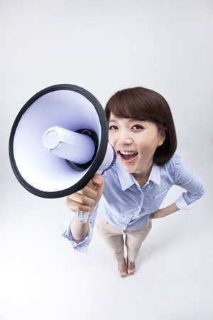 Portrait of from above Asian female teacher shouting with loudspeaker isolated on whiteの写真素材