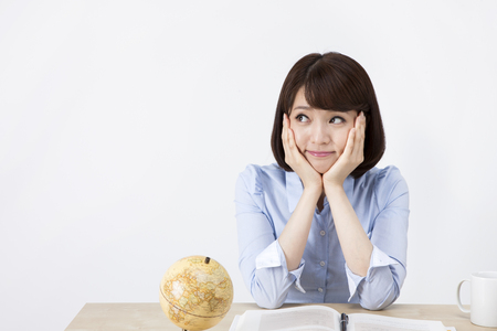 Portrait of Asian female teacher thinking something on the desk isolated on whiteの写真素材