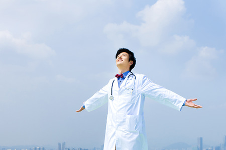 Portrait of Asian male doctor feel freedom with blue skyの写真素材