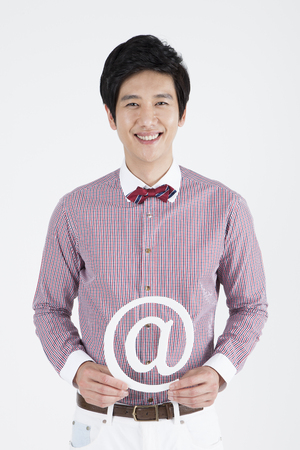 Portrait of Asian male teacher holding paper cutout internet icon isolated on whiteの写真素材