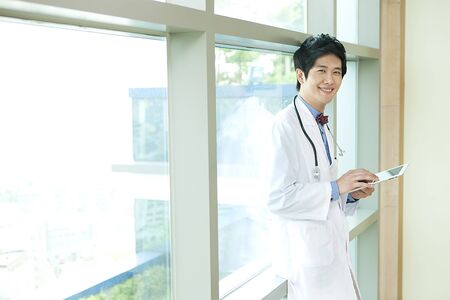Portrait of Asian male doctor using tablet with smile indoorの写真素材