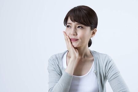Portrait of Asian stressful woman having toothache isolated on whiteの写真素材