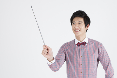 Portrait of Asian male teacher pointing something with teaching stick isolated on whiteの写真素材