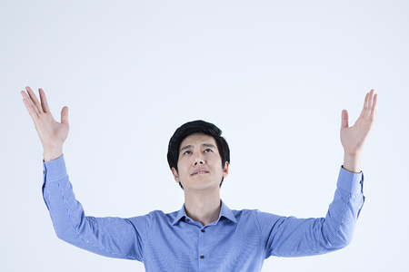 Portrait of Asian stressful man acting angry with putting his arms up isolated on whiteの写真素材