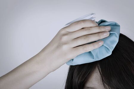Portrait of Asian woman with ice bag for headaches and migraines isolated on whiteの写真素材