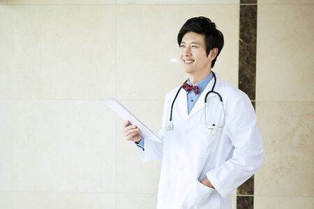 Portrait of Asian male doctor holding document in hospitalの写真素材