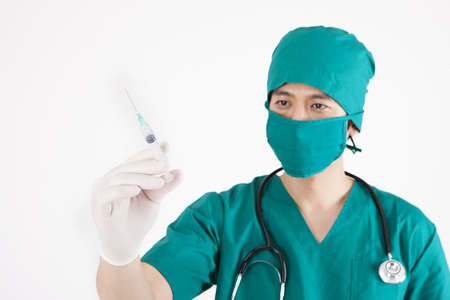 Portrait of Asian male surgeon in mask with syringe isolated on whiteの写真素材