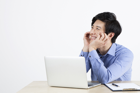 Portrait of Asian handsome teacher happy thinking gesture with laptop on the desk isolated on whiteの写真素材