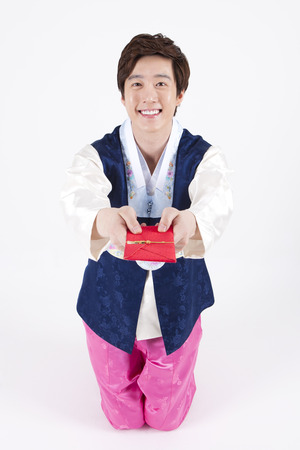 Asian handsome man in Korean traditional clothes giving gift card isolated on whiteの写真素材