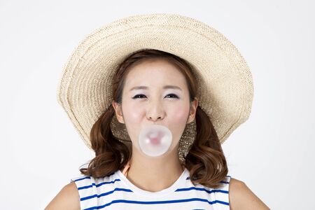 Portrait of Asian beautiful woman blowing bubble gum with smile on summer day isolated on whiteの写真素材