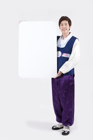 Asian man in Korean traditional clothes holding white board isolated on whiteの写真素材