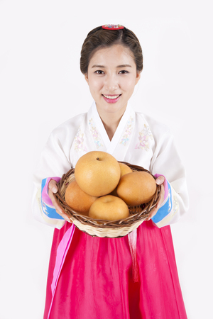 Asian woman in Korean traditional clothes holding fruit basket isolated on whiteの写真素材