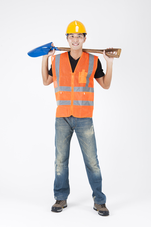 Asian handsome man in industry helmet with shovel isolated on whiteの写真素材