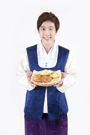 Asian man in Korean traditional clothes holding Korean pancake isolated on whiteの写真素材