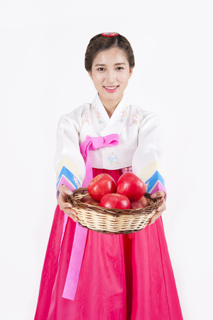 Asian woman in Korean traditional clothes holding apple basket isolated on whiteの写真素材