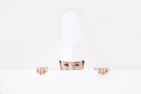 Asian female chef behind white board isolated on whiteの写真素材