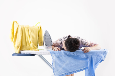 Asian housewife in apron does the ironing hard isolated on whiteの写真素材