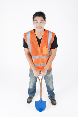 Asian handsome man in industry helmet with shovel isolated on whiteの写真素材