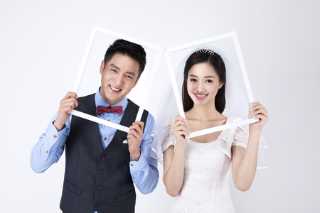 Asian happy couple holding frame isolated on whiteの写真素材