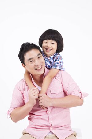 Asian dad carrying son on his back isolated on whiteの写真素材