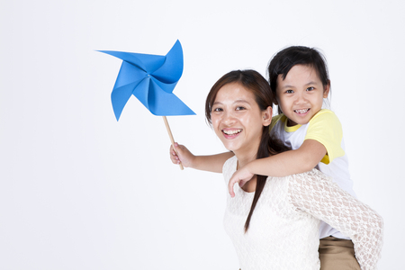 Asian multicultural family mother and daughter with pinwheel isolated on whiteの写真素材
