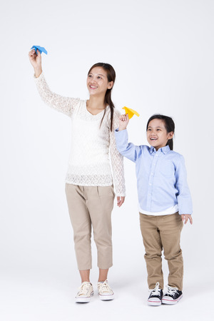 Asian multicultural family mother and daughter with paper airplane isolated on whiteの写真素材