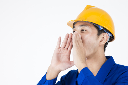 Asian male Engineers in industry helmet calling somebody isolated on whiteの写真素材