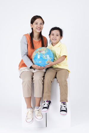 Asian multicultural family mother and daughter with globe isolated on whiteの写真素材