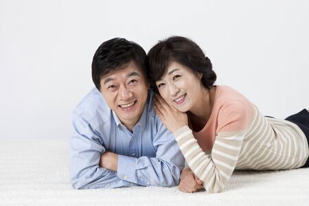 Asian middle aged couple lying on lug isolated on whiteの写真素材